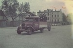 Ghetto firefighters ride in the back of a fire truck through the Lodz ghetto.