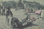 A vendor sits under a shade umbrella in the outdoor market of the Lodz ghetto.