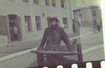 A bearded member of the transportation crew pulls a wooden cart through a street of the Lodz ghetto.