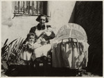 Portrait of a woman with her two small children posing in front of a house.