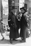 Religious Jews converse on a busy street in the Warsaw ghetto.