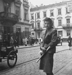 A well-dressed woman poses on a commercial street in the Warsaw ghetto.