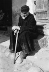An elderly Jewish man sits on a step outside a door in an unidentified ghetto.
