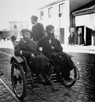 Two religious Jewish men travel by rickshaw in the Warsaw ghetto.