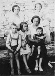 A group of women and children from Olkusz pose together on a log.