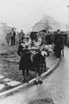 Two Polish women carry wreaths of flowers at a memorial observance after the war.