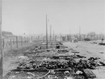 Corpses lie in a pile beside the charred ruins of barracks in the Kaufering IV concentration camp.