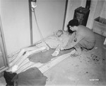 Sargeant Joseph Perlman, of the U.S. Third Army, oversees the intravenous system that feeds this Jewish survivor.