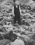 SS officer Johann Baptist Eichelsdoerfer, the commandant of the Kaufering IV concentration camp, stands among the corpses of prisoners killed in his camp.