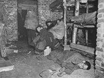 Survivors wrapped in blankets sit among the dead inside of a barracks in Woebbelin.