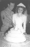 A Jewish bride and groom pose cutting their wedding cake.