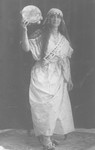 A young Jewish woman dressed up for Purim as the biblical figure Miriam, poses with a tambourine.