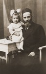Studio portrait of a Jewish grandfather holding his granddaughter.