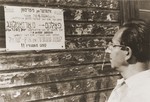 Julius Sutin reads an announcement posted on the outside of a building in the Neu Freimann displaced persons camp inviting camp residents to come to the children's plaza to hear Yitzchak Retner speak on recent events in Palestine.