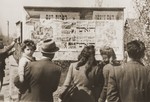 Jewish DPs read announcements and posters posted on an outdoor bulletin board in the Neu Freimann displaced persons camp.