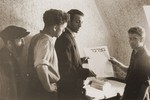 Jewish DPs working in the publications office of the Neu Freimann displaced persons camp hold up the latest issue of the Bamidbar [In the Wilderness] newspaper.