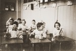 Young Jewish children sit at tables in the childcare center at the Joodsche Schouwburg in the Amsterdam Jewish quarter.