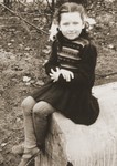 Portrait of Stefa Friedfertig sitting on a cement block that she used as her playground in the Belsen DP camp.