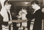 Three boys wrap a small Torah scroll during a service at the synagogue of the Baruch Auerbach Jewish orphanage in Berlin.