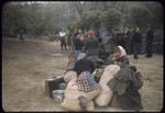 Displaced persons wait next to their suitcases and bundles.