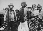 The chief (Vajda) of a Roma group stands in the center, flanked by a man and two women.