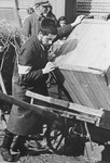 A religious Jewish youth loads a large crate onto a cart in the Krakow ghetto.