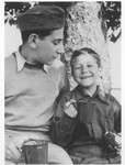 Two brothers who were members of the Buchenwald children's transport sit under a tree.