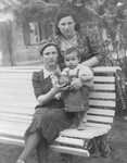 Two Jewish refugee women pose with a child on a park bench in Kaidan, Lithuania.