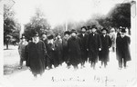 The Gerer Rebbe, Rabbi Abraham Mordecai Alter, walks along a street of a resort town accompanied by a group of his followers.