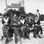 A group of young Jewish men and women sit on a bench in Vilna's Cathedral Square.