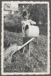 Ruth Landau, an Austrian Jewish girl, waters her garden with a large watering can.