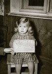 Toddler Hidrun de Maere poses with a name card intended to help any of her surviving family members locate her at the Kloster Indersdorf DP camp.