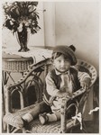 A young Jewish boy wearing a tam sits in a chair at his home in Kazimierz.