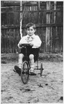 Dov Zugman rides his tricycle in a yard in Sokol.