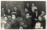 A large group of adults and children gathers together inside a room in the Lodz ghetto.