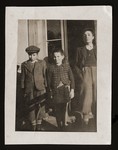 Three Jewish siblings pose on the porch of a house.