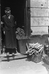 A religious Jew poses in the doorway of a shop in the Warsaw ghetto from which he is selling coal and kindling.