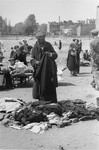 An elderly Jewish man examines used clothing at an open air market in the Warsaw ghetto.