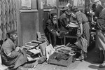 A woman purchases kindling from a street vendor in the Warsaw ghetto.