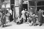 A group of Jews are gathered in front of a vegetable store owned by Jochewet Abzac in the Warsaw ghetto.