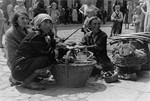 Three women sell household items on the street in the Warsaw ghetto.