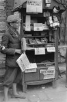 A teenage vendor sells newspapers and armbands in the Warsaw ghetto possibly on Muranowski Square.
