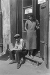 A barefoot woman and a young man in the doorway of a shoemaker's shop in the Warsaw ghetto.