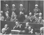 Defendants in the International Military Tribunal war crimes trial in Nuremberg sit in the prisoners' dock in front of a row of American military police.