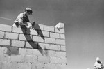 A man constructs a brick wall in Tel Shachar.