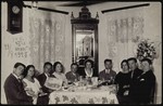 A group of young people enjoys a social gathering around a table set with coffee cups and plates.
