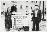 Two young Jewish DPs pose next to a sign at the entrance to the Bindermichl displaced persons camp near Linz, Austria.