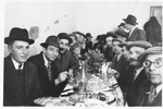 Jewish DPs are gathered around a table at a festive meal following the circumcision of Arele Werkel, the son of Taibel and Yehiel Greenberg at the Ebelsberg displaced persons camp near Linz, Austria.