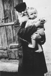 An elderly Jew holds a small baby in an unidentified ghetto in Poland.