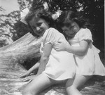 Annette and Margo Lederman, two Jewish children in hiding, pose in a tree on the farm of the van Buggenhout family.